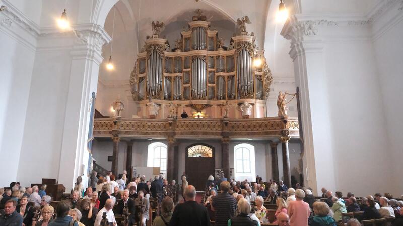 Eine volle Kirche, viele Menschen blicken zur Orgelempore.