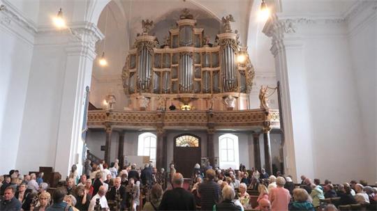 Eine volle Kirche, viele Menschen blicken zur Orgelempore.