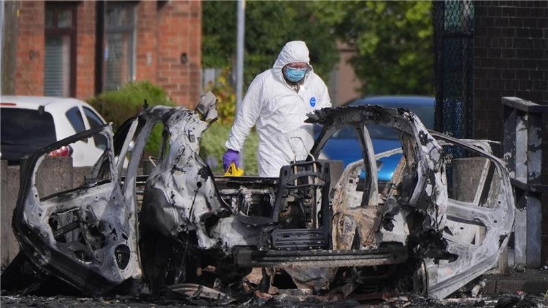 Nach einer Explosion vor einer Polizeistation steht ein Ermittler neben einem zerstörten Auto in Dunmurry, nahe Belfast in Nordirland. 
