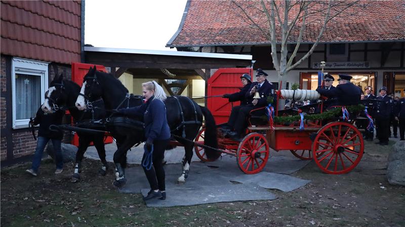 Pferdespritze nimmt ihren Platz im Kleinen Spritzenhaus ein Zwei schwarze Pferde ziehen eine rote Kutsche mit vier uniformierten Männern. Nach einer Fahrt durchs Dorf bringen die Pferde die historische Spritze zum neuen Unterstand.