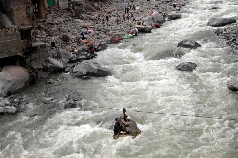 Nach schweren Überschwemmungen überqueren Menschen im pakistanischen Bahrain einen Fluss mithilfe einer Seilbahn.