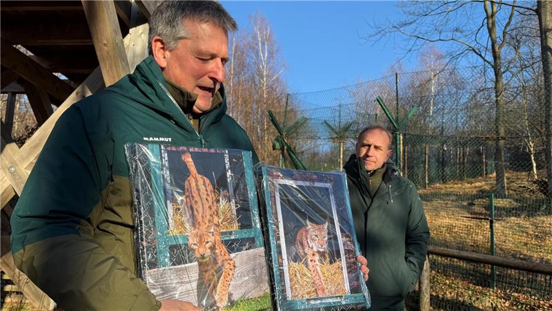Nationalparkleiter Dr. Roland Pietsch (l.) und der Luchsbeauftragte Ole Anders überreichen Bilder der beiden Zuchtluchse.