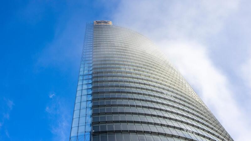 Nebelschwaden ziehen an der Zentrale von DHL, dem Posttower, vorbei. Oben angebracht ist ein Posthorn-Logo.