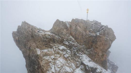 Nebelwolken umhüllen bei Schneetreiben auf der Zugspitze die Aussichtsplattform mit dem Gipfelkreuz (Archivbild). Aus mehreren Bergsteigergruppen wurden Notrufe abgesetzt, nachdem sie aufgrund von Witterung und Neuschnee auf etwa 2500 Metern Höhe nicht mehr weiterkamen.