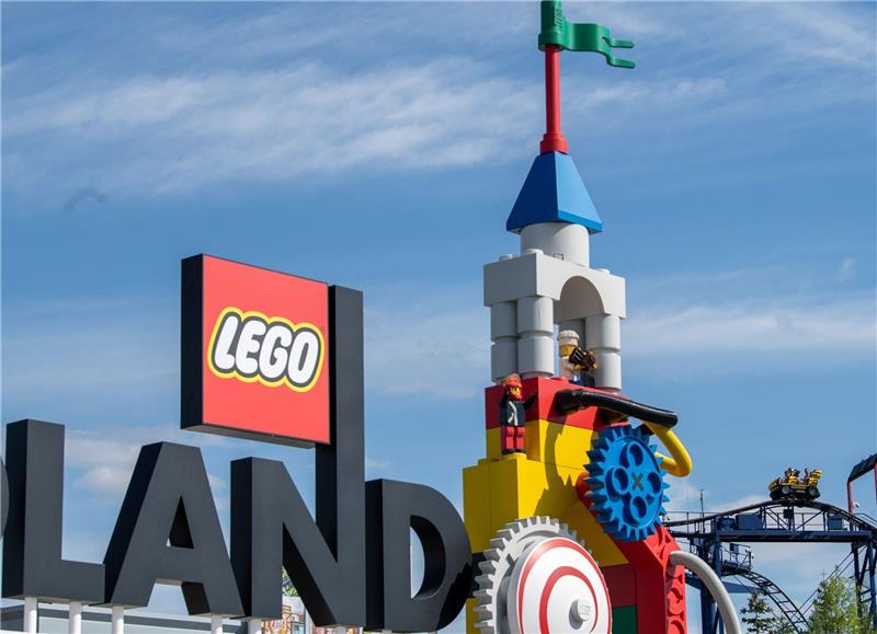 Neben dem Logo am Eingang zum Legoland ist eine Achterbahn (r) zu sehen. Bei einem Unfall auf einer Achterbahn im Legoland sind im August 2022 im schwäbischen Günzburg 31 Menschen verletzt worden.
