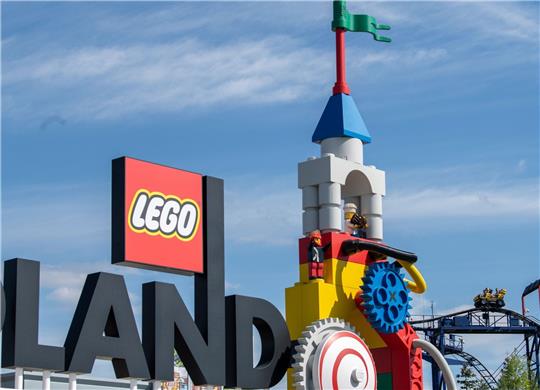 Neben dem Logo am Eingang zum Legoland ist eine Achterbahn (r) zu sehen. Bei einem Unfall auf einer Achterbahn im Legoland sind im August 2022 im schwäbischen Günzburg 31 Menschen verletzt worden.