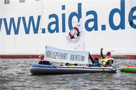 Neben der «Aida Diva» halten Klimaaktivisten ein Transparent mit der Aufschrift «Kreuzfahrt (K)entern».
