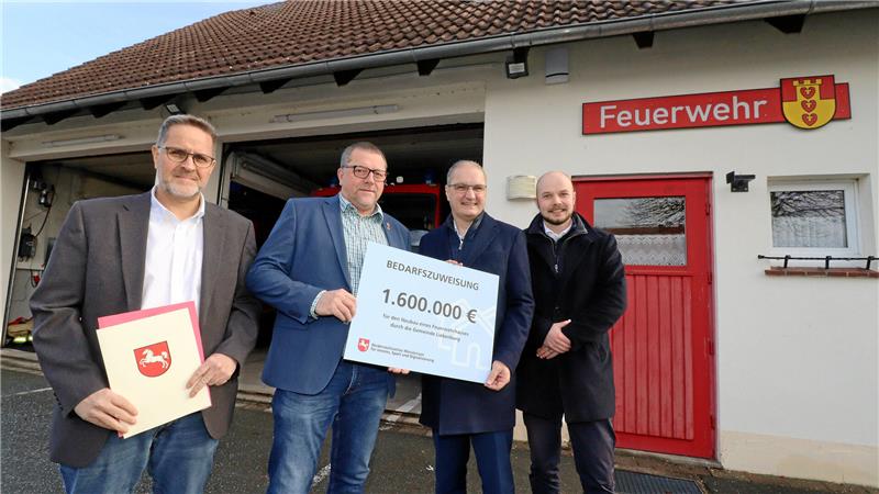 Vier Personen präsentieren eine Mappe mit dem niedersächsischen Landeswappen und einen symbolischen Scheck.