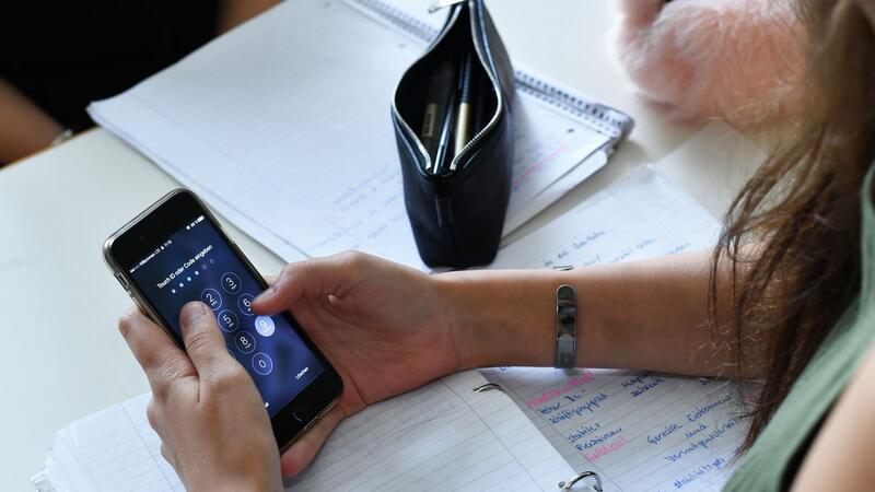 Hand hält Smartphone mit geöffnetem Taschenrechner auf einem Tisch mit Notizblock, Stiftetui und handschriftlichen Notizen
