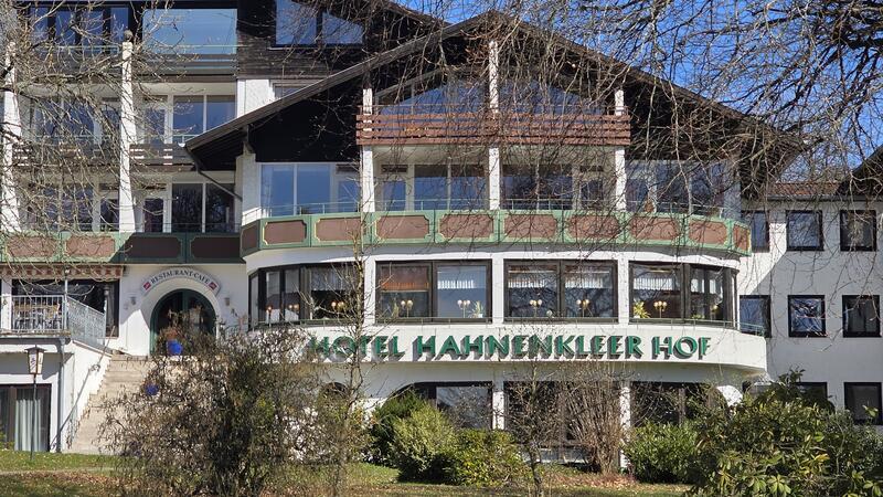 Fassade eines mehrstöckigen Hotels mit Schriftzug 'HOTEL HAHNENKLEER HOF' und kahlen Bäumen im Vordergrund