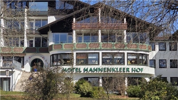 Fassade eines mehrstöckigen Hotels mit Schriftzug 'HOTEL HAHNENKLEER HOF' und kahlen Bäumen im Vordergrund
