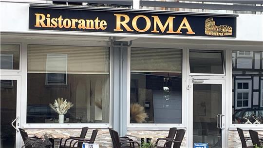 Außenansicht eines Restaurants mit dem Schriftzug 'Ristorante ROMA' und einer Abbildung des Kolosseums über dem Eingang