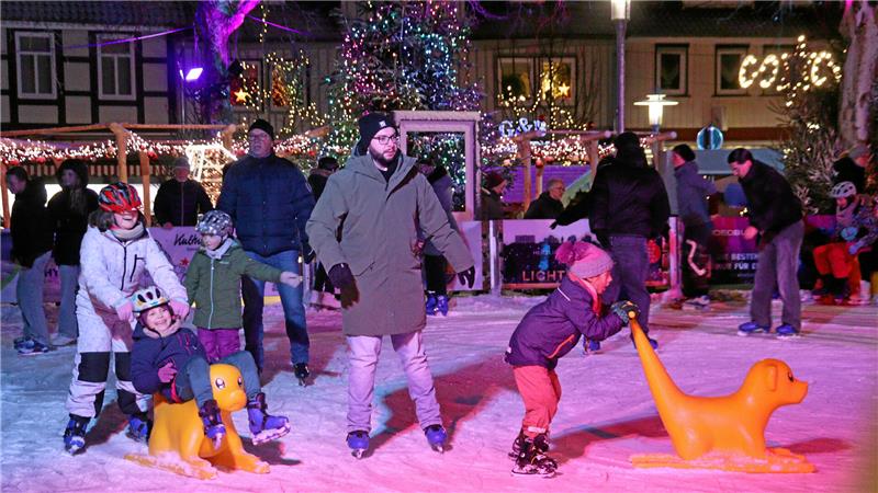 Menschen auf Schlittschuhen vergnügen sich auf einer Eisbahn.