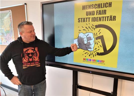 Nils Oskamp vor einem seiner Plakate gegen die Identitäre Bewegung, die den Staat und die Demokratie in Frage stellt.