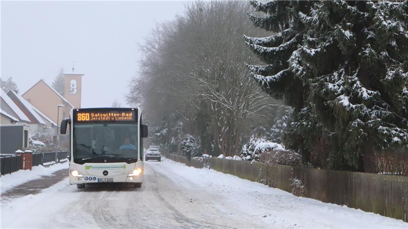 Linienbus fährt auf einer verschneiten  Straße. 
