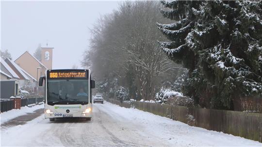 Linienbus fährt auf einer verschneiten  Straße. 