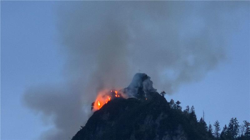 Noch immer steigen große Rauchwolken aus einem bewaldeten Berg bei Ruhpolding (Landkreis Traunstein) auf.