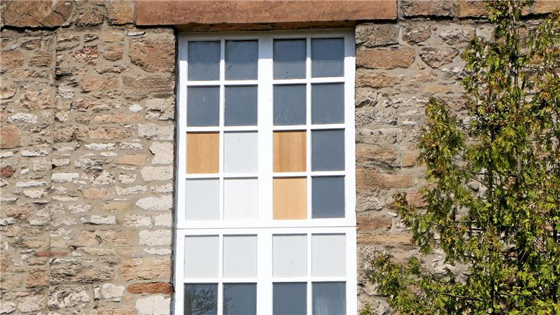 Notdürftig verschlossene Fenster erinnern von außen noch an den Brand: Die Einsatzkräfte hatten Scheiben eingeschlagen, damit Rauchgase abziehen können.