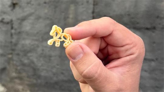 Eine Hand, die eine Nudel in Pferdeform hält.