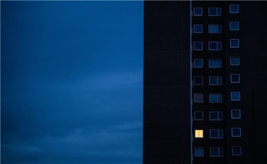 Nur einer Wohnung eines Mehrfamilienhauses brennt am frühen Morgen Licht. Die teils massiv gestiegenen Preise für Gas und Strom bereiten viele Menschen in Deutschland finanzielle Schwierigkeiten.