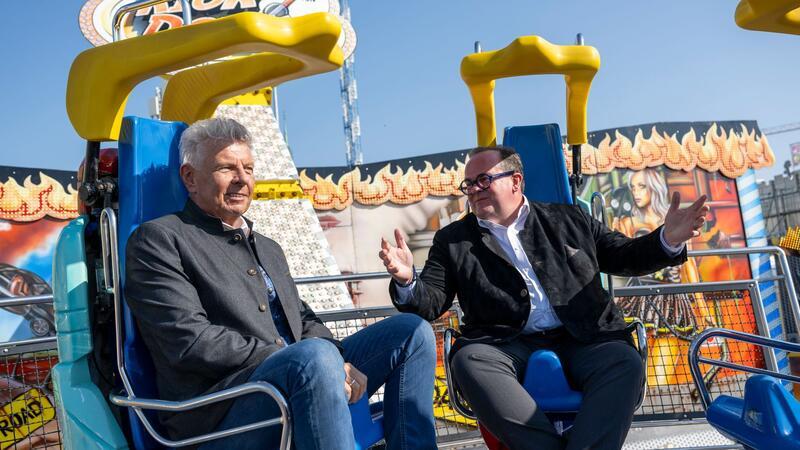 Oberbürgermeister und Festleiter testen vor dem Start ein Fahrgeschäft.