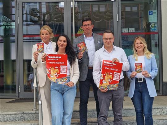 Oberbürgermeisterin Urte Schwerdtner (links), Camilla Dal Pos (2. v. l.) und Jannick Voß (2. v. r.) von der Stadtjugendpflege, Sparkassen-Regionaldirektor Jens Müller (Mitte) und Mara-Lena Macke vom Fachdienst Bildung und Soziales (rechts) präsentieren den Ferienpass 2024. Foto: Schlimme