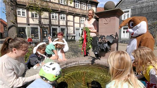 Österliche Tradition: Cordula Wulf klettert auf den Hornburger Marktbrunnen, um am Wasserauslass ein Kranz zu befestigen.