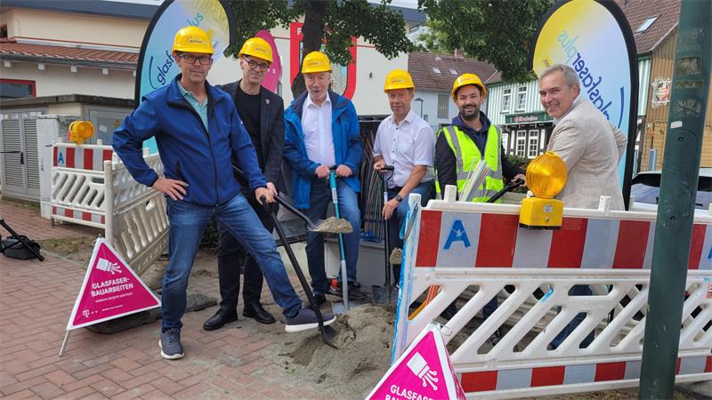 Sechs Männer stehen vor einem Verteilerschrank und halten Spaten in der Hand.