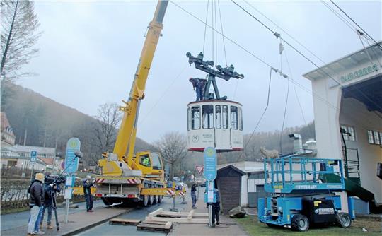 Ohne Zuschauer, aber begleitet von einem Fernseh-Team des NDR wird die Kabine Nummer 1 der Burgberg-Seilbahn am Donnerstagmorgen von einem Kran aus ihrem Tragseil gehoben. Wegen des stürmischen Wetters beginnt die Aktion zu einer windschwächeren Phase in aller Frühe, denn starke Böen hätten die frei schwebende Gondel und die Männer auf ihrem Dach gefährden können. Foto: Nachtweyh