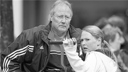 Zwei Personen, eine mit Adidas-Jacke, die andere mit Kapuzenpullover, stehen nah beieinander