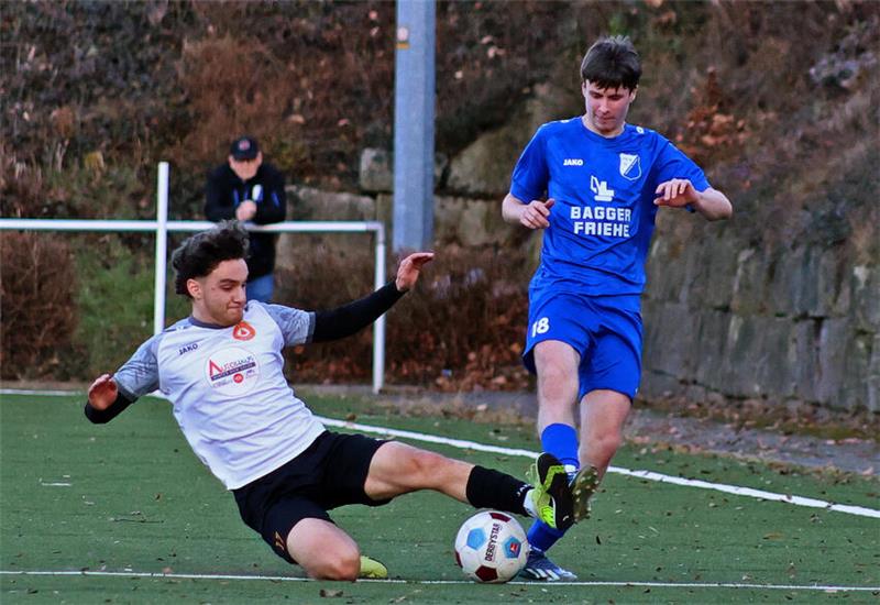 Zwei Fußballspieler kämpfen um den Ball, einer rutscht auf dem Boden
