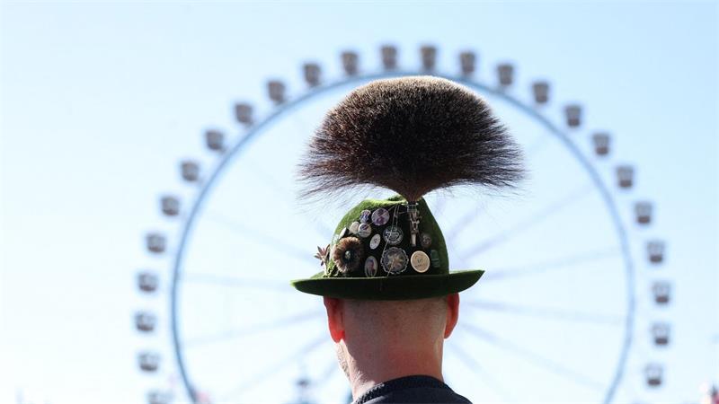 Oktoberfest 2026: ein Mann mit Gamsbart steht am ersten Wiesn Tag vor dem Riesenrad.