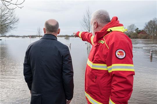 Olaf Scholz (l) steht mit einem Helfer der DLRG an einem überfluteten Gebiet in Verden/Aller.
