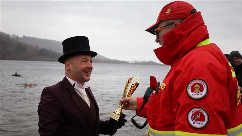 Mann im Anzug mit Zylinder bekommt einen Pokal
