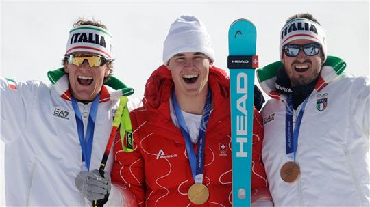 Olympiasieger Franjo von Allmen wird flankiert von Silber-Gewinner Giovanni Franzoni (links) und dem Drittplatzierten Dominik Paris.