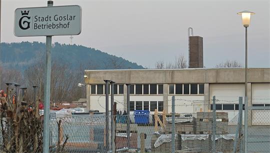 Betriebshof mit Zaun, Gebäuden und einem Schild mit der Aufschrift 'Stadt Goslar Betriebshof' vor bewaldetem Hügel im Hintergrund