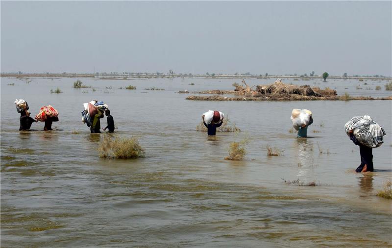 Opfer der schweren Überschwemmungen durch Monsunregen tragen in der Provinz Sindh Hilfsgüter durch das Hochwasser.