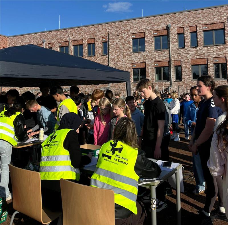 Goslarer CvD-Gymnasium erläuft 8500 Euro für „Girls in Action“ Menschenmenge vor einem Zelt mit Personen in gelben Warnwesten, die an Tischen sitzen und mit anderen sprechen, vor einem Backsteingebäude