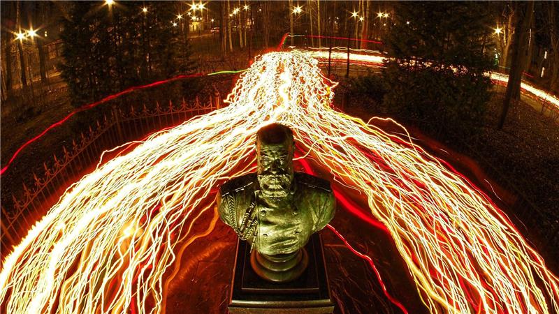 Orthodoxe Gläubige gehen während des orthodoxen Mitternachtsgottesdienstes zu Ostern mit Kerzen an einer Büste des russischen Zaren Alexander III. in St. Petersburg vorbei.  (Foto mit Langzeitbelichtung)