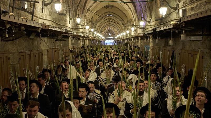 Orthodoxe jüdische Männer beten während der Morgengebete zum jüdischen Laubhüttenfest (Sukkot) vor dem Tor des Souq Al-Qattanin.