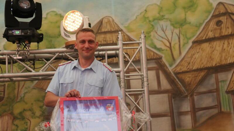 Ortsbrandmeister Florian Rowold zeigt das Präsent der Partnerfeuerwehr aus Preetz.