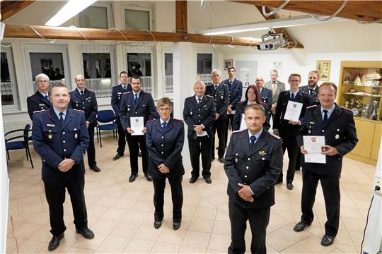 Ortsbrandmeister Marcus Saß (vorn links) und sein Stellvertreter Patrick Maibaum (von rechts) sowie Kreisbrandmeister Uwe Fricke (2. Reihe links) und Bürgermeister Ralf Abrahms (im Hintergrund) mit den Geehrten und Beförderten Feuerwehrleuten. Foto: Schlegel