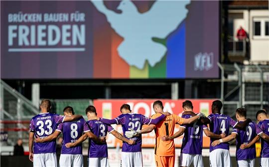 Osnabrücks Spieler stehen bei einer Schweigeminute für den Frieden auf dem Platz.
