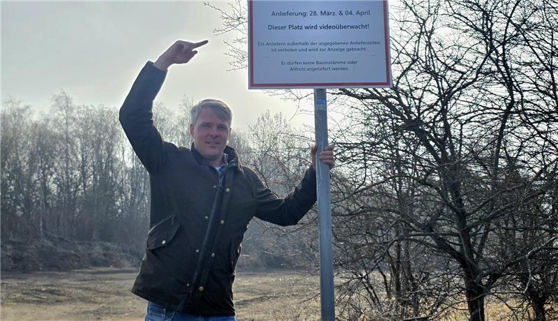 Osterfeuer: Diese Termine stehen in Goslar und Oker fest Mann zeigt auf ein Schild, dass auf ein baldiges Osterfeuer hinweist.