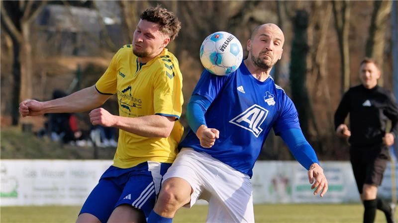 Zwei Fußballspieler in gelbem und blauem Trikot kämpfen um den Ball in der Luft auf einem Spielfeld