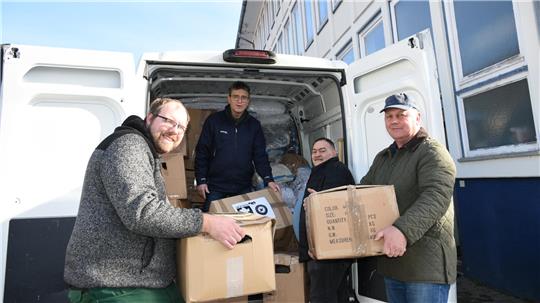 Vier Männer beladen einen weißen Transporter, der schon gut gefüllt ist.