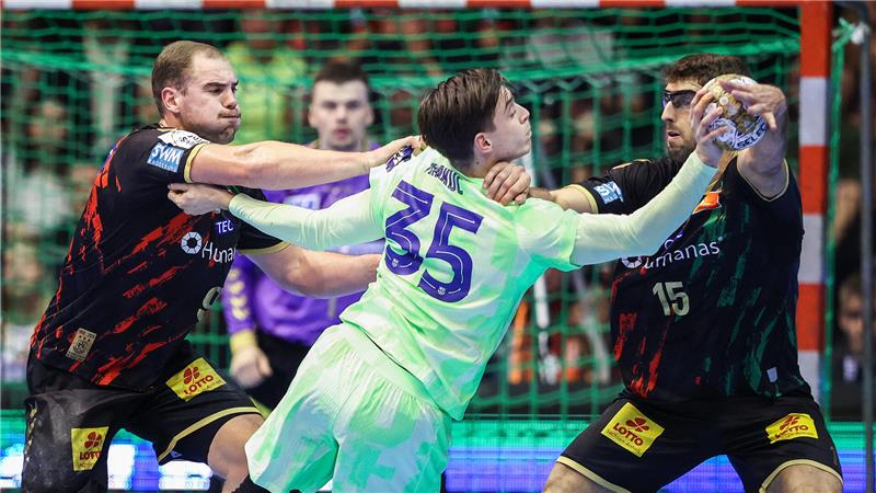 Drei Handballspieler in Aktion vor dem Tor, zwei in schwarzen Trikots mit gelben Logos und einer in weißem Trikot mit der Nummer 35, der Ball wird vom Spieler rechts gehalten.