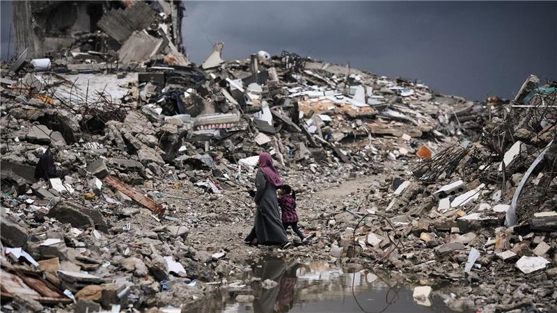 Palästinenser gehen bei stürmischem Wetter durch die Trümmer in Gaza.