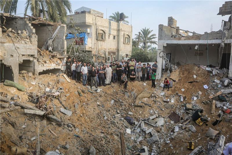 Palästinenser stehen in Chan Junis im Gazastreifen um einen Krater herum, der durch einen israelischen Angriff verursacht wurde.