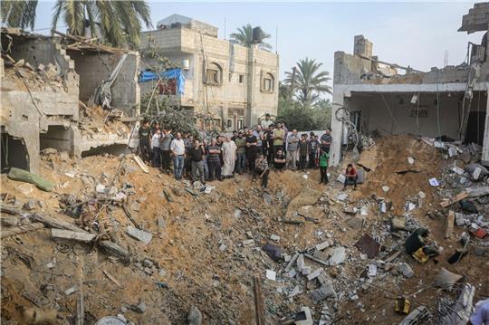 Palästinenser stehen in Chan Junis im Gazastreifen um einen Krater herum, der durch einen israelischen Angriff verursacht wurde.
